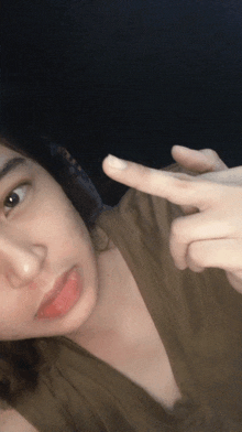a woman in a brown shirt is pointing her finger at something