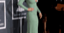 a woman in a green dress is standing on a red carpet at a grammy awards event .
