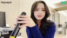 a young woman in a blue sweater is holding a microphone in her hand .