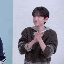 a young man wearing a sweater is clapping his hands