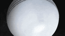 a close up of a white cricket ball on a black surface