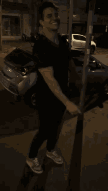 a man in a black shirt is standing next to a street sign that says ' avenida ' on it