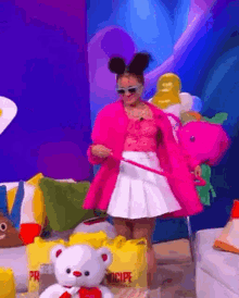 a woman in a pink coat and white skirt is holding a teddy bear