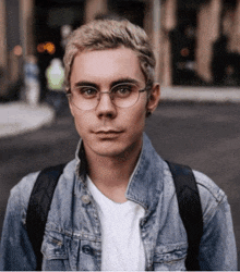 a man wearing glasses and a denim jacket