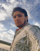 a man in a green and white floral shirt looks at the camera