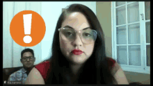 a woman wearing glasses and red lipstick looks at the camera with an exclamation point behind her