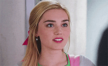 a close up of a blonde woman 's face with a pink bow in her hair