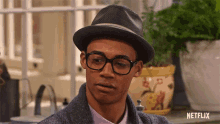 a man wearing glasses and a hat is standing in front of a netflix logo