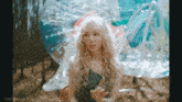 a woman with blonde hair and a cat nose is sitting in a clear bubble