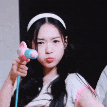 a girl wearing a white headband is holding a pink and blue water gun