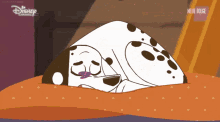 a dalmatian dog is laying on a bed with a disney channel logo on the bottom