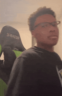 a blurry picture of a person wearing glasses and a s-racer gaming chair
