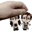 a hand is holding two small figurines over their heads .