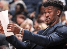 a man in a suit is holding a piece of paper in his hand
