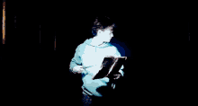 harry potter is holding a wand in his hand and reading a book .