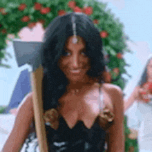 a woman in a black dress is holding a large axe and smiling .