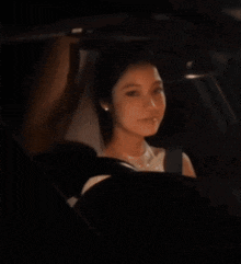 a woman is smiling while driving a car in the dark