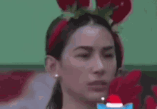a woman wearing a reindeer headband is smiling and waving .