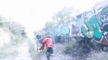 a person in a red jacket is running in front of a wall with graffiti on it that says ' a ' on it