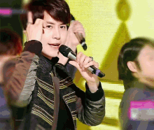 a man is holding a microphone in his right hand and making a peace sign