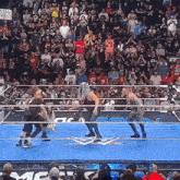 a group of wrestlers are wrestling in a ring with a crowd watching .