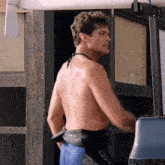 a shirtless man is standing in front of a door with a surfboard hanging from it