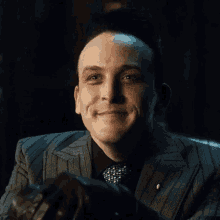 a man in a suit and tie is smiling and holding a gun in his hand .
