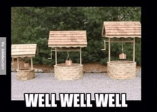 three wooden wishing wells are lined up in a row in a gravel area .