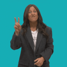 a woman wearing a black jacket and a white t-shirt that says converse is making a peace sign