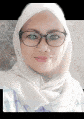a woman wearing glasses and a white hijab looks at the camera