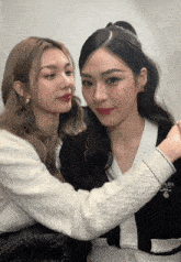 two women are posing for a picture and one has a cardigan that says prada on it