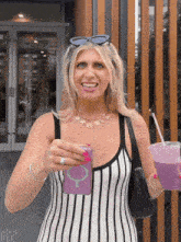 a woman in a black and white striped dress is holding a drink