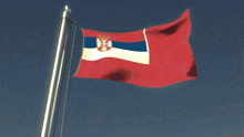 a red white and blue flag is waving in the wind against a blue sky
