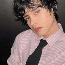 a young man wearing a pink striped shirt and a black tie