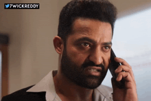 a man with a beard is talking on a cell phone with the hashtag 7wickreddy