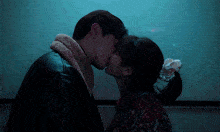 a man and a woman kissing in front of a white board