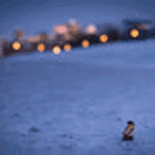 a blurry picture of a person standing in the snow with a train in the background .