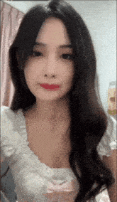 a woman with long black hair is wearing a white top