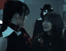 two girls are looking at each other in a dark room with a man in a mask in the background .