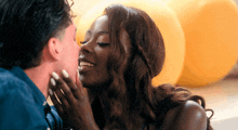 a man is kissing a woman on the cheek in front of yellow balloons