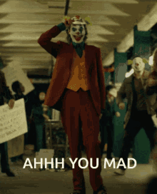 a man in a joker costume stands in front of a sign that says ahhhh you mad