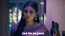 a woman in a purple saree is standing in a room with bottles of wine .