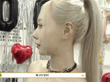 a woman in a ponytail stands in front of balloons and a sign that says 00