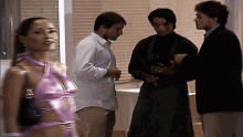 a woman in a pink top is standing in a room with three men