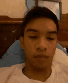 a young man is sitting on a bed with his eyes closed and making a funny face .