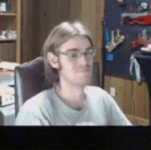 a man wearing glasses is sitting in a chair and looking at the camera