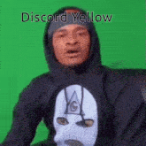 a man wearing a mask and a hoodie with the words `` discord yellow '' on it .