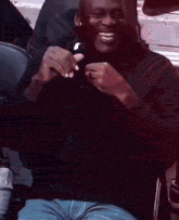 a man wearing a black jacket and blue jeans is sitting in a chair