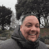 a man wearing a black jacket with a hood is smiling