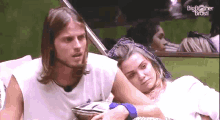 a man and a woman are sitting next to each other with the big brother brasil logo behind them